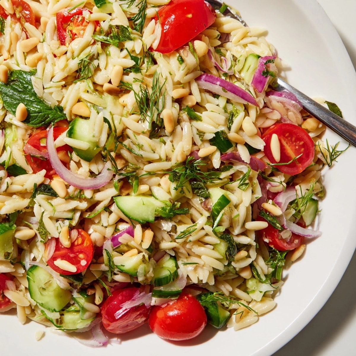Bright Lemon Herb Orzo Salad: close-up shows tossed, herby goodness with juicy tomatoes.