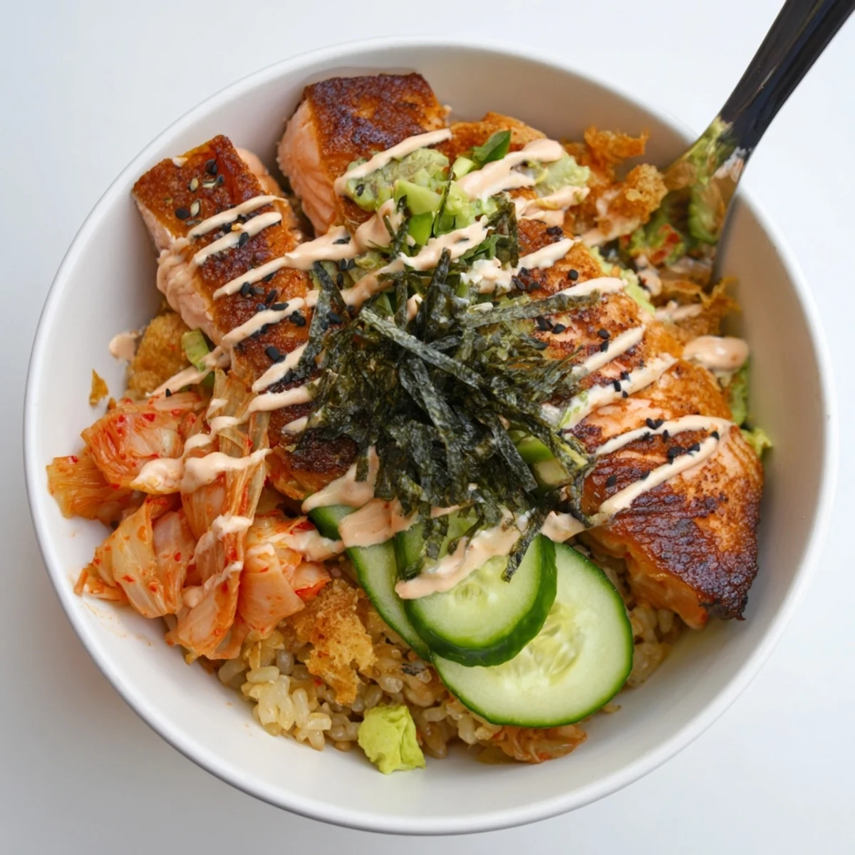 Enjoy a hearty Crispy Salmon Rice Bowl, featuring golden rice and vibrant cucumber slices.