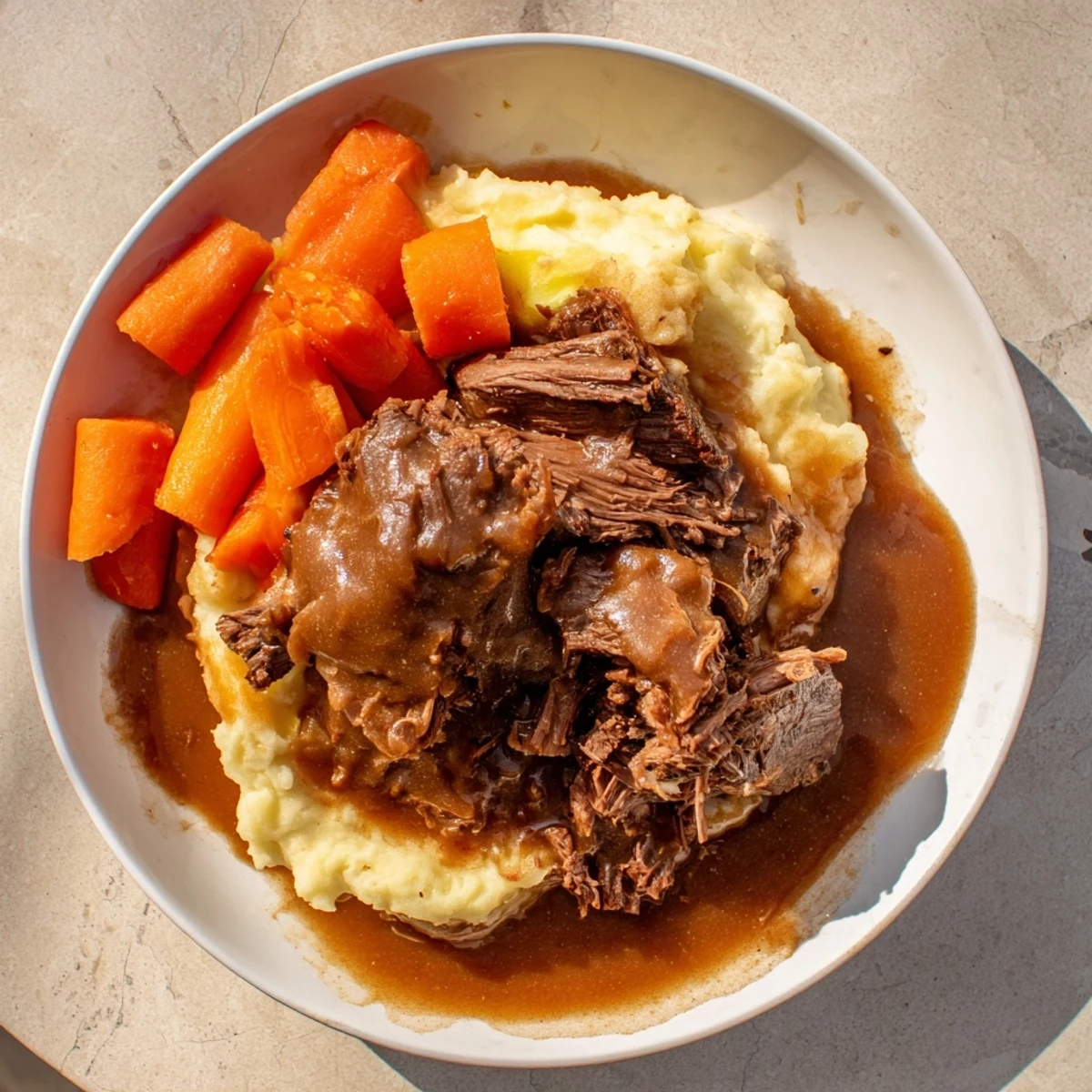 Hearty American dinner: a steaming plate of Slow Cooker Pot Roast and beautifully textured mashed potatoes.
