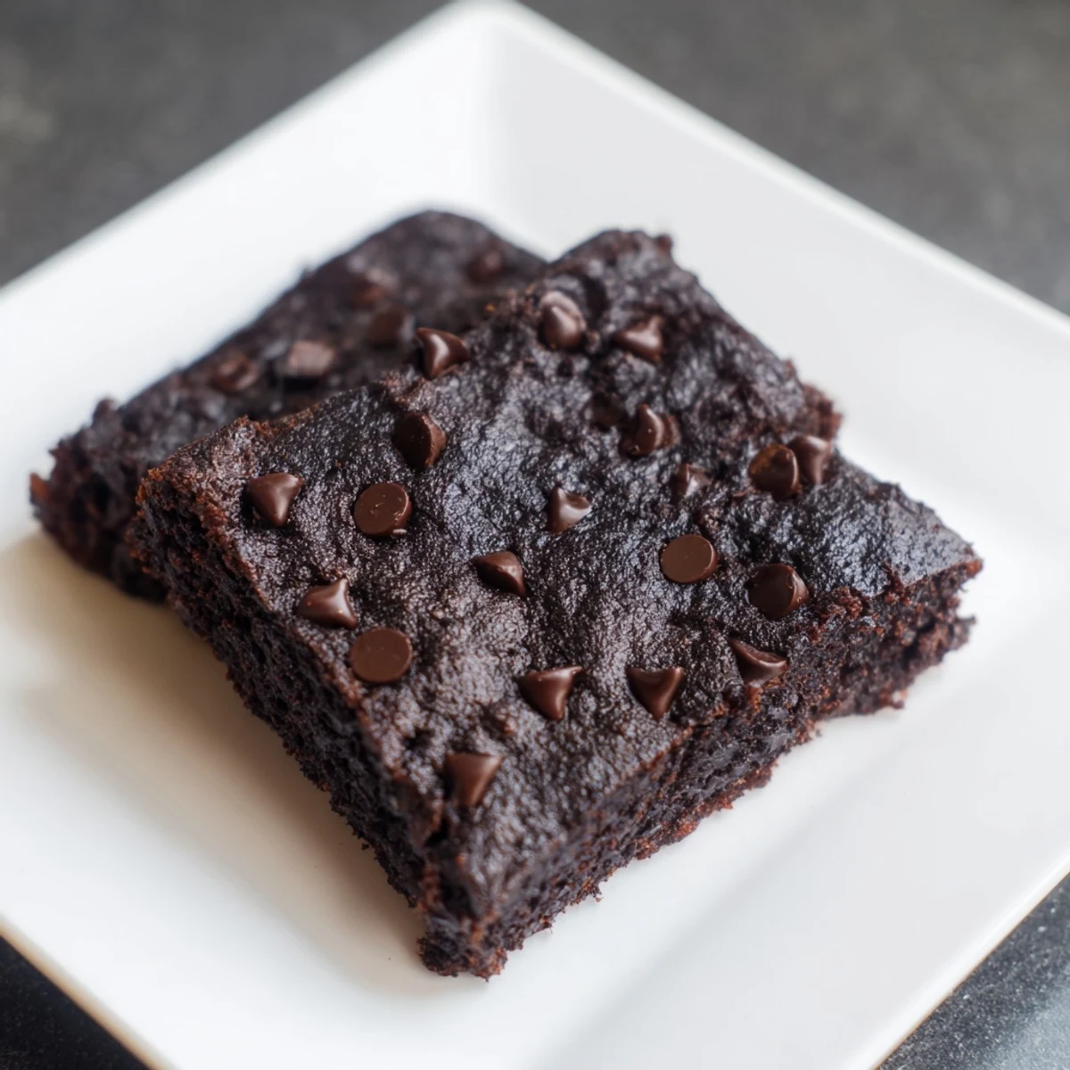 A square of rich Black Bean Brownies, perfectly baked, ready to serve with a scoop of vanilla ice cream.