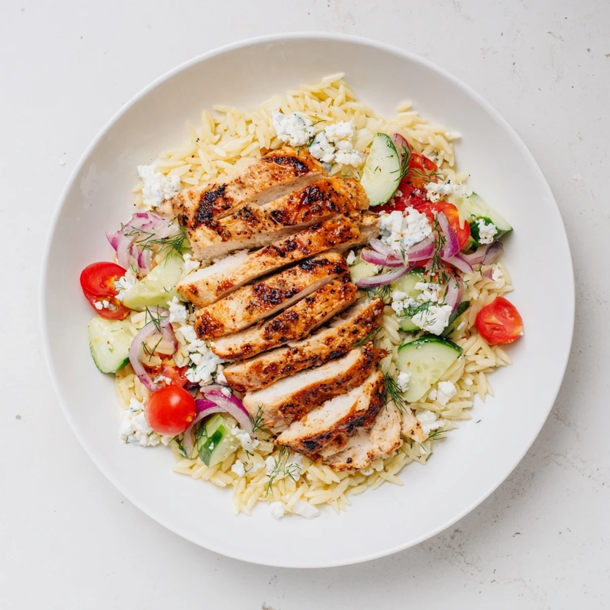 The bright colors of tomatoes and cucumbers showcase this Greek Chicken Gyro Pasta Bowl, a flavorful Mediterranean delight.