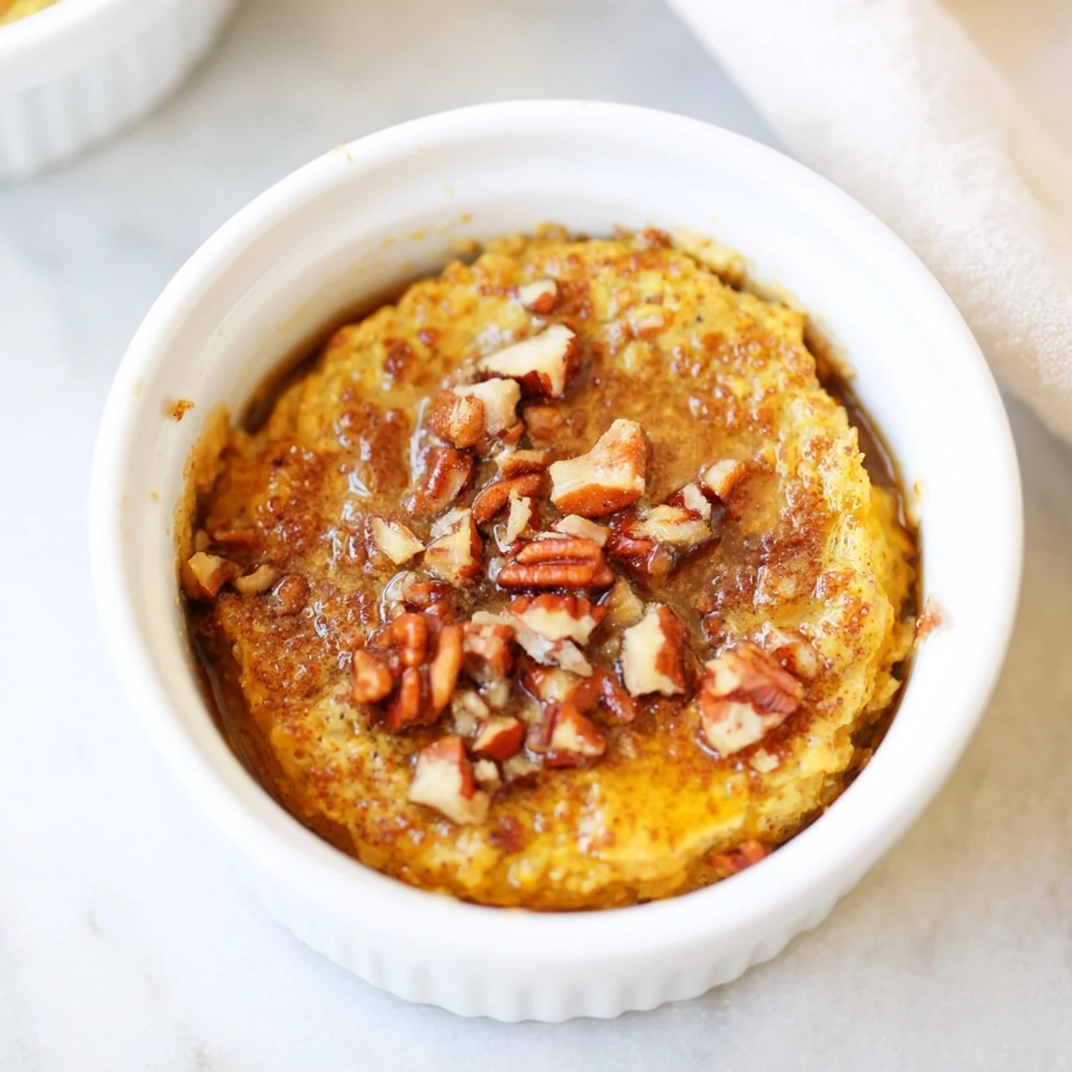 A close-up of fluffy pumpkin spice baked oats, topped with pecans, ready to enjoy this cozy morning.