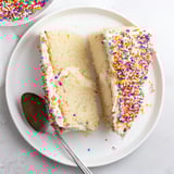 Imagine the sweetness! A beautifully decorated Happy Birthday Cake slice with fluffy white frosting, ready to eat.