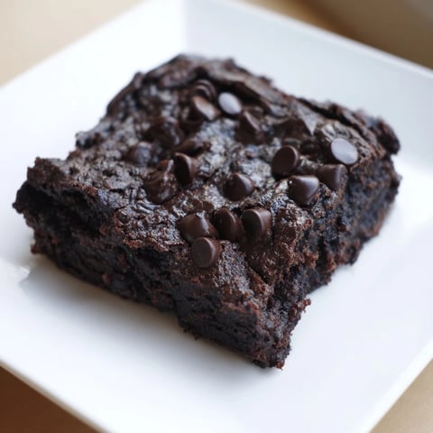 Warm, fudgy Black Bean Brownies, topped with melted chocolate chips, a delicious gluten-free dessert option.