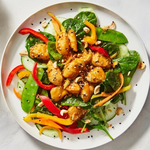 High-Protein Chicken Stir-Fry Salad Bowl with colorful veggies, sesame seeds, and a delicious dressing.