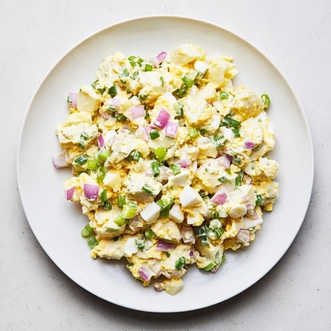 A vibrant bowl of Chopped Egg and Potato Salad, garnished with fresh herbs and ready to serve.