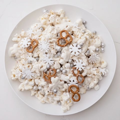 A festive Ski Season Snowflake Snack Mix, coated in white chocolate and snowy sprinkles.
