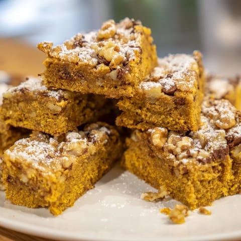 Warmly spiced Holiday Snack Pumpkin Nut Bars surrounded by fallen autumn leaves.  