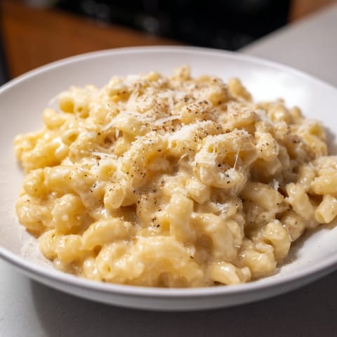 A close-up of creamy, bubbling mug mac & cheese, ready in minutes with melted cheddar cheese.
