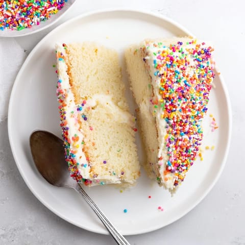 Imagine the sweetness! A beautifully decorated Happy Birthday Cake slice with fluffy white frosting, ready to eat.