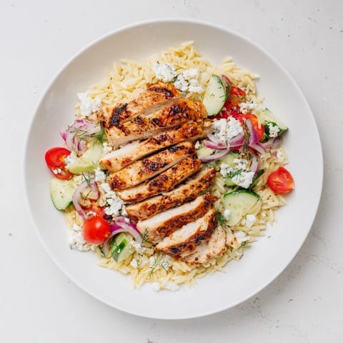 The bright colors of tomatoes and cucumbers showcase this Greek Chicken Gyro Pasta Bowl, a flavorful Mediterranean delight.
