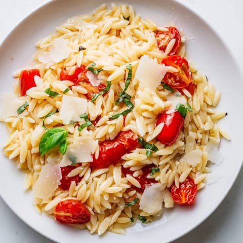Bright, colorful bowl of orzo tomato Parmesan, tossed with juicy tomatoes and grated Parmesan, ready to serve.