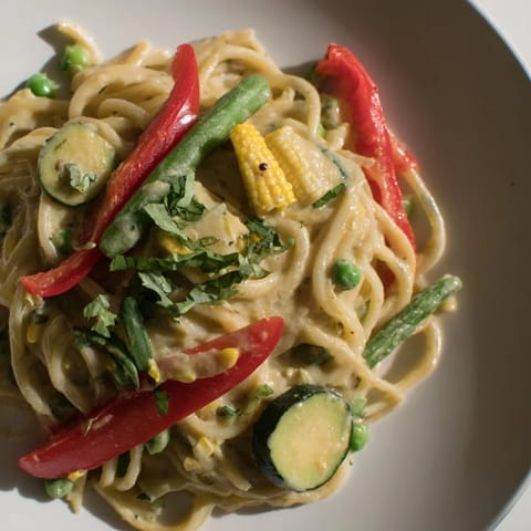 This vibrant photo showcases the rich, aromatic Thai Curry Pasta with fresh cilantro and lime garnishes.