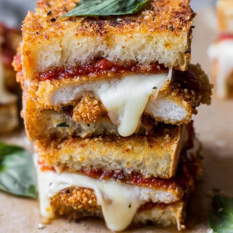 Slices of Chicken Parm Grilled Cheese reveal layers of marinara, mozzarella, and crunchy panko chicken.