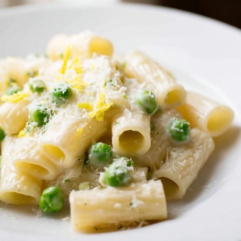 Creamy pea and lemon ricotta pasta tossed in al dente rigatoni, topped with fresh basil leaves for a bright spring main dish.