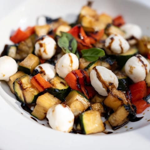 Serving of warm Roasted Veggie Caprese Salad featuring caramelized cherry tomatoes and fresh basil leaves, perfect as a colorful side dish or light vegetarian lunch.  