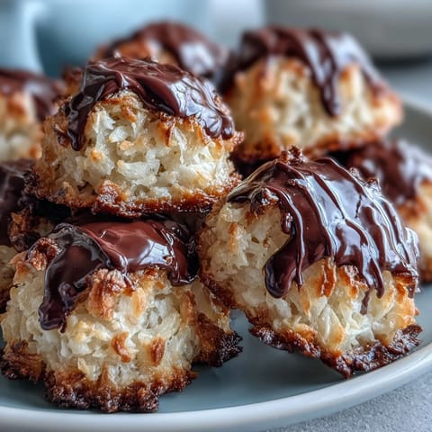 Close-up of a platter of Vegan Coconut Macaroons with Dark Chocolate Drizzle, highlighting glossy chocolate topping and toasted coconut, ready to serve with coffee.