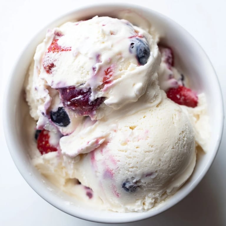 Enjoy a scoop of this healthy cottage cheese ice cream, with vibrant red and blue berry pieces.