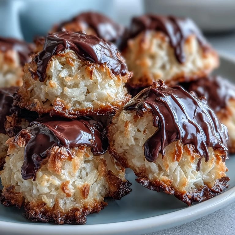 Close-up of a platter of Vegan Coconut Macaroons with Dark Chocolate Drizzle, highlighting glossy chocolate topping and toasted coconut, ready to serve with coffee.